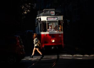 Woman crossing in front of a vintage tram in Istanbul's Moda district at dusk.