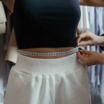 Detailed view of a tailor measuring a client's waist in a clothing workshop, focusing on precision.